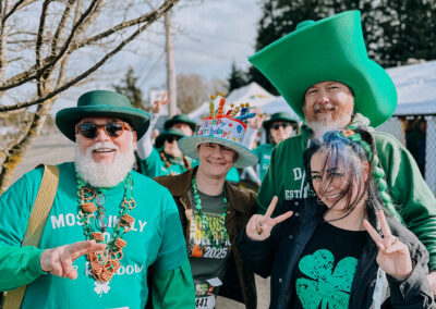 Group of participants wearing green shamrock hats and festive outfits posing together at the 2025 Poulsbo Beer Run in Poulsbo, Washington.
