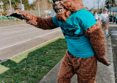 Person dressed as Sasquatch wearing a teal event shirt during the 2025 Poulsbo Beer Run in downtown Poulsbo.