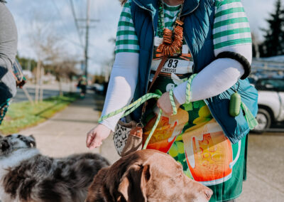 Participant in green attire walking two dogs during the 2025 Poulsbo Beer Run in Poulsbo, Washington.