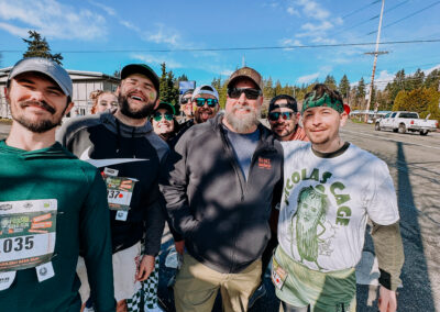 Wide group photo of participants wearing green outfits during the 2025 Poulsbo Beer Run.