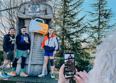 Participants posing at the Norseman statue while being photographed during the 2025 Poulsbo Beer Run.