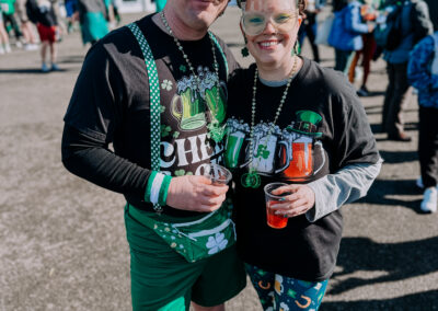 Couple wearing coordinated green St. Patrick’s Day outfits holding drinks at the 2025 Poulsbo Beer Run.