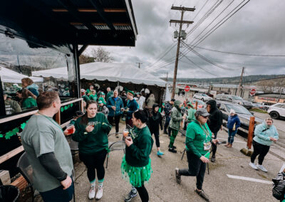Large outdoor crowd mingling near event tents during the 2025 Poulsbo Beer Run.